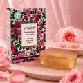 Sabonete VegSkin Óleo de Rosa Mosqueta 90g da GHDERMA: caixa com estampa floral e barra glicerinada âmbar translúcida sobre pedra rosa com pétalas de rosa